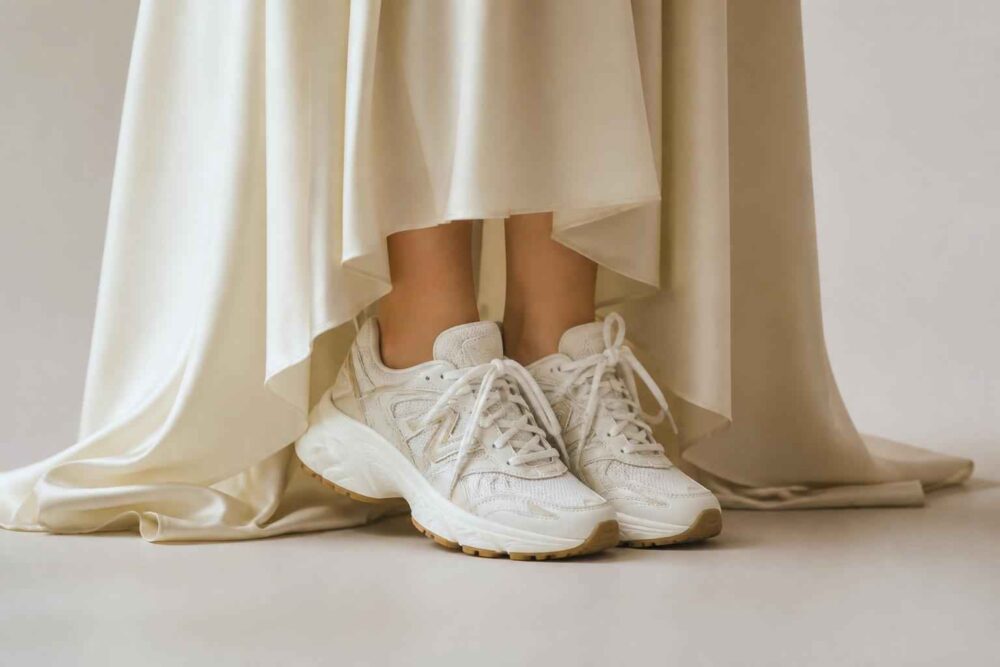 Białe buty sportowe pod suknią Białe sneakersy wystające spod eleganckiej, kremowej sukni