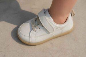 Biały dziecięcy sneaker z paskiem i gumową podeszwą na nodze